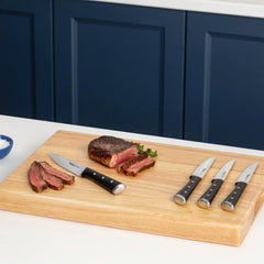 Sliced steak on cutting board with knives beside it.