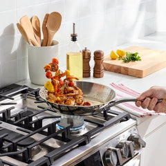 Shrimp and vegetables being sautéed in a skillet on a gas stove.