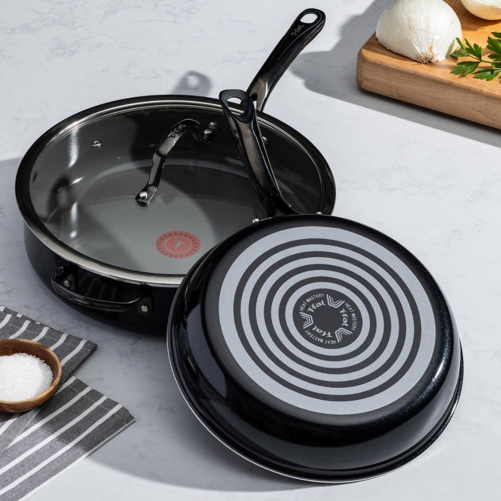 Two pans on a kitchen counter; one upright with black interior, one upside down showing red Thermospot. Ingredients nearby.