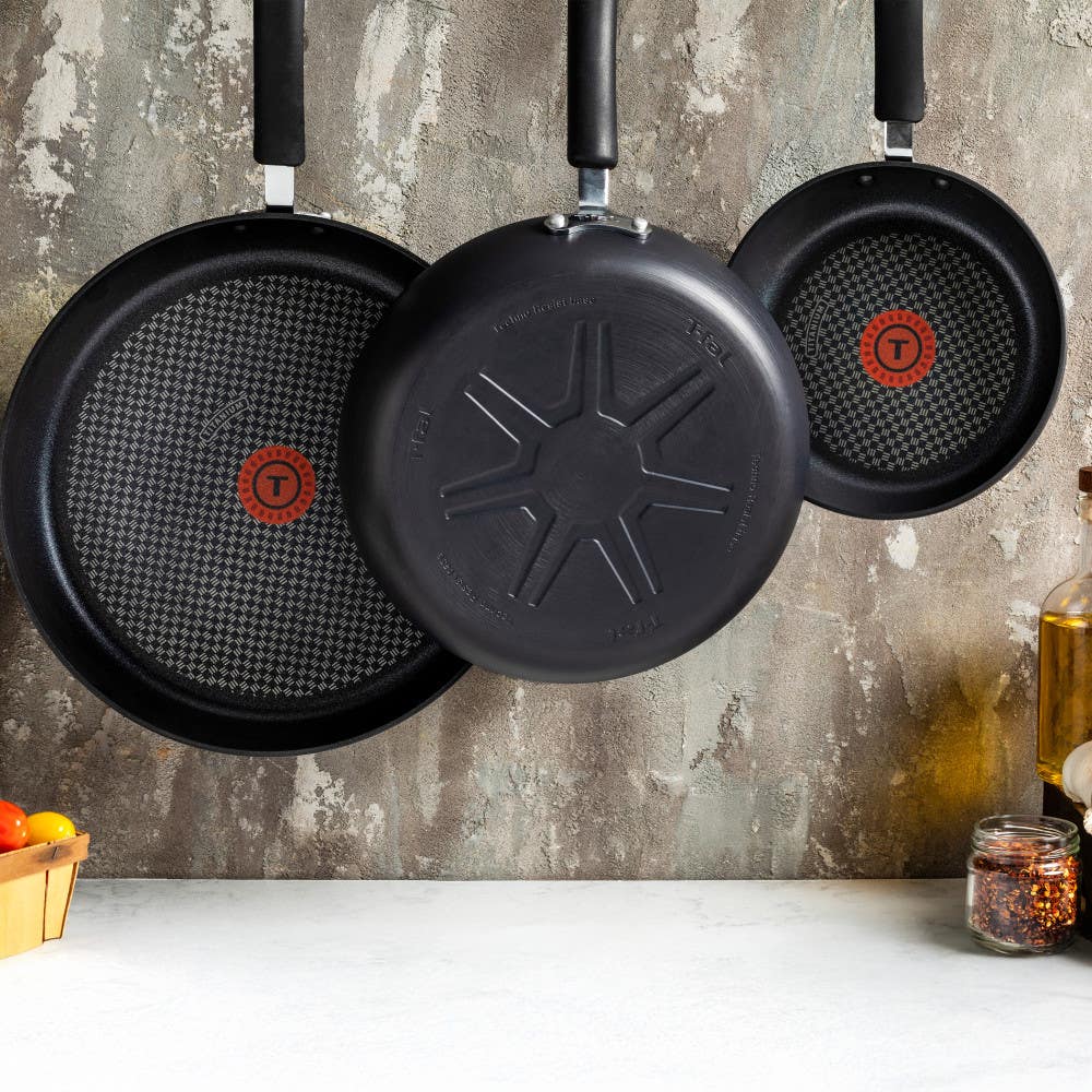 Three black frying pans hanging on wall, showing non-stick interior and base
